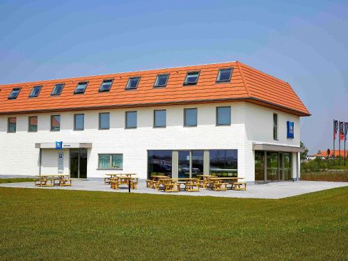 un bâtiment avec bancs et tables devant lui dans l'établissement ibis budget Oostende Airport, à Ostende