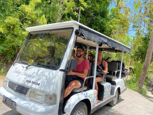 um grupo de pessoas andando em um carrinho de golfe em Bintang Bungalow em Nusa Penida