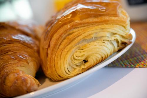 um prato de croissants e outros produtos de pastelaria numa mesa em Kyriad Prestige Beaune le Panorama em Beaune