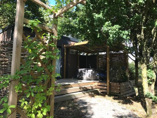 eine hölzerne Pergola mit einem Whirlpool im Hof in der Unterkunft Cottage du garlai in Bressuire