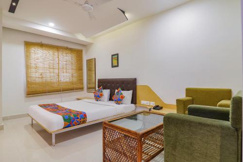 1 Schlafzimmer mit einem Bett und 2 Stühlen in der Unterkunft FabHotel Aamantran & Banquet Halls - Nr Snow World Hyderabad in Hyderabad