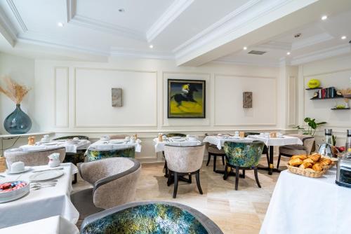 a restaurant with tables and chairs and a painting on the wall at Queens Boutique Hotel in Paris