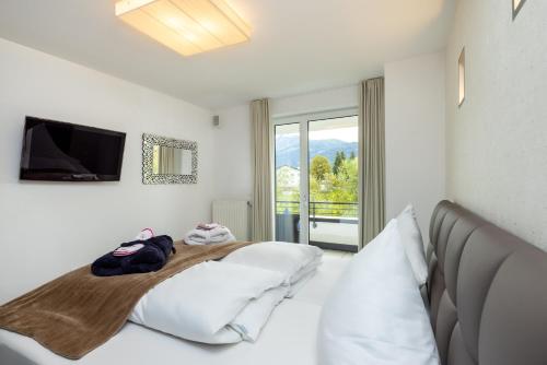 ein weißes Schlafzimmer mit einem Bett und einem TV in der Unterkunft Enjoy ONE in Altenmarkt im Pongau