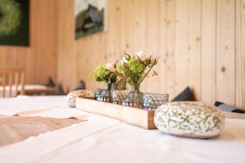 een tafel met twee stoelen en vazen met bloemen erop bij Schlegelhof in Kirchzarten