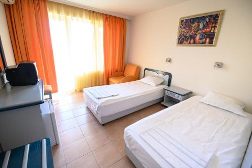 um quarto de hotel com duas camas e uma cadeira em Hotel Iskar & Aquapark - All Inclusive em Sunny Beach