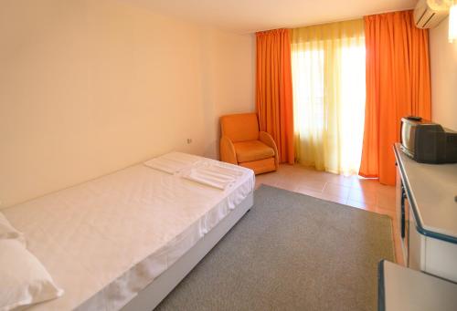 um quarto com uma cama e uma cadeira laranja em Hotel Iskar & Aquapark - All Inclusive em Sunny Beach