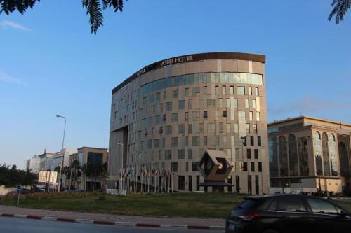 um carro estacionado em frente a um grande edifício em Hotel Royal ASBU Tunis em Tunes