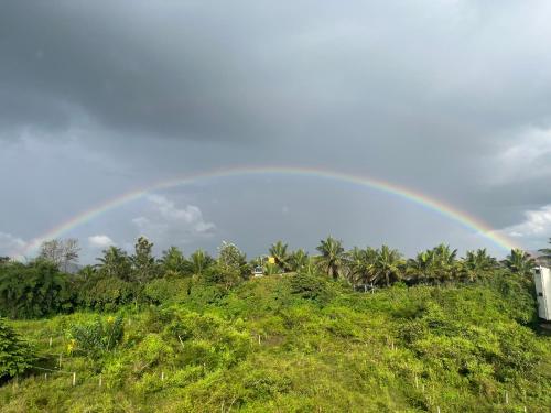 Un arcobaleno nel cielo su una collina di Darshan Arrive & Revive Homestay. a Kushalnagar