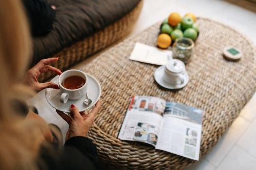 a woman holding a cup of tea on a coffee table at Dome Hotel in Rīga