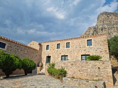 un bâtiment en pierre avec une montagne en arrière-plan dans l'établissement Lazareto Hotel, à Monemvasia