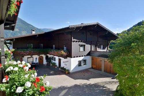 uma casa com uma cerca e flores à frente dela em Riemenerhof em Fügen