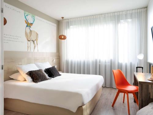 1 dormitorio con cama, escritorio y silla en ibis Styles Rennes St. Gregoire, en Saint-Grégoire