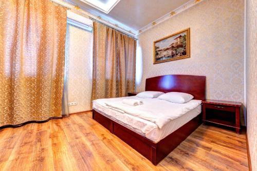 um quarto com uma cama, piso em madeira e uma janela em Hotel Kiev Lomakin em Kiev