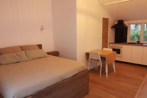 a bedroom with a bed and a table and a kitchen at Au Bord de l'Oise in Auvers-sur-Oise