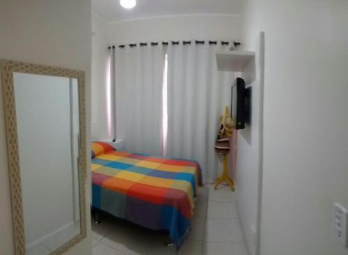 1 dormitorio con 1 cama colorida y espejo en Apto em Cabo Frio com conforto e qualidade., en Cabo Frío