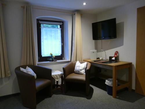 ein Hotelzimmer mit einem Schreibtisch, einem Stuhl und einem TV in der Unterkunft „Frische Quelle“ Jonsdorf in Kurort Jonsdorf