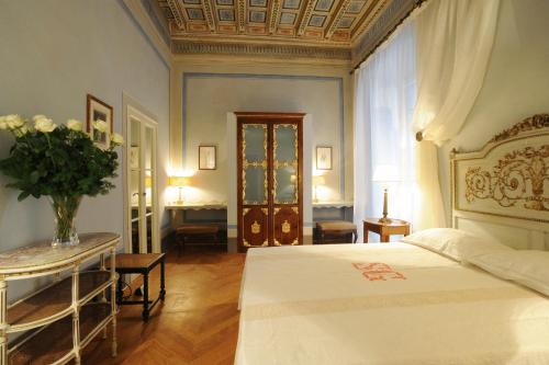 een slaapkamer met een bed en een tafel met een vaas met bloemen bij Palazzo Rocchi - Residenza D'Epoca in Lucca