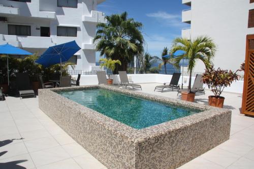 a swimming pool in a resort with chairs and a building at Amapas Apartments Puerto Vallarta in Puerto Vallarta