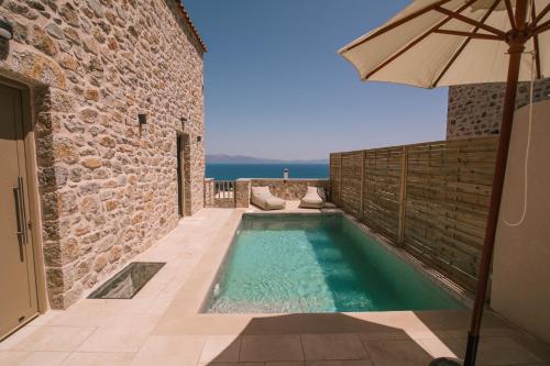 Mani Luxury Suites and Studios in Gytheio with Private Pools في غيتيو: مسبح مع مظله بجانب مبنى