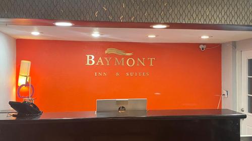 奥德萨Baymont Inn by Wyndham Odessa University Area的橙色的墙壁,上面标有巴蒙特旅馆和套房的标志