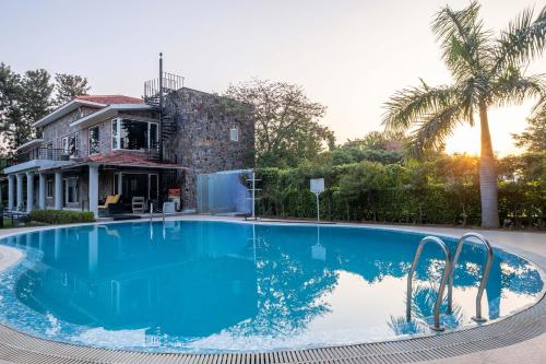 a large blue swimming pool in front of a house at StayVista at The Banyan Abode with Pool Table, Pet Friendly & Outdoor Pool in Manesar