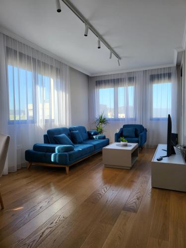 uma sala de estar com sofás azuis e uma televisão em Green Apartments Podgorica With Garage em Podgorica