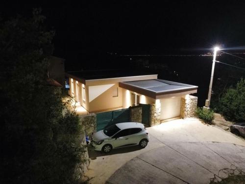 une voiture garée devant une maison la nuit dans l'établissement Casa M Montenegro, à Donji Morinj