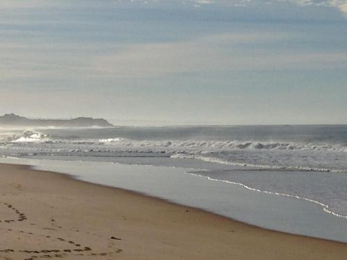 une plage de sable avec des vagues dans l'océan dans l'établissement MH Atlantico, à Peniche