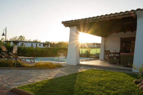 un patio con pergolato e piscina di Capannizza Villas a Budoni