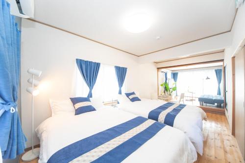 two beds in a small room with blue curtains at Yokkaichi Motomachi Hotel in Yokkaichi