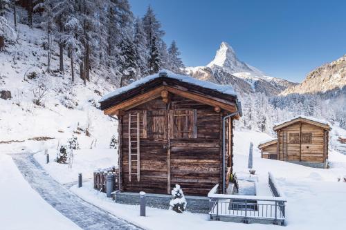 eine Holzhütte im Schnee mit einem Berg in der Unterkunft Piccola Fiamma by Pizzo Fiamma in Zermatt