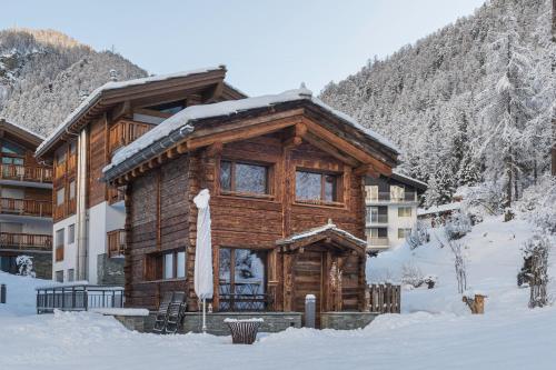 ein Blockhaus im Schnee vor einem Gebäude in der Unterkunft Piccola Fiamma by Pizzo Fiamma in Zermatt