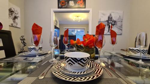 a glass table with a bowl and plates and wine glasses at Stunning Holiday Home. Free Parking. in Manchester