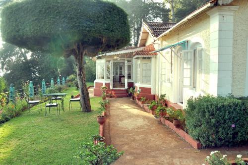 een huis met een tafel en een boom in de tuin bij Wyoming Heritage in Ooty