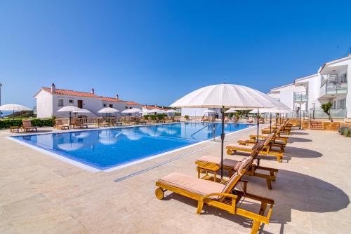 een zwembad met stoelen en parasols in een resort bij Naranjos Resort Menorca in S'Algar