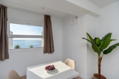 ein weißes Esszimmer mit einem Tisch und einem Fenster in der Unterkunft Apartamentos Venecia in Lloret de Mar