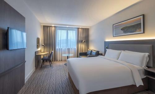 um quarto de hotel com uma grande cama branca e uma secretária em Radisson Blu Hotel Dublin Airport em Cloghran