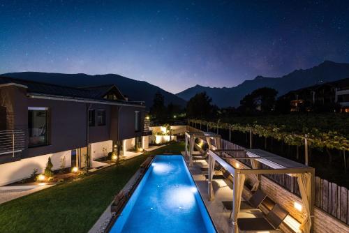 een achtertuin met een zwembad in de nacht bij Merangardenvilla adults only in Merano