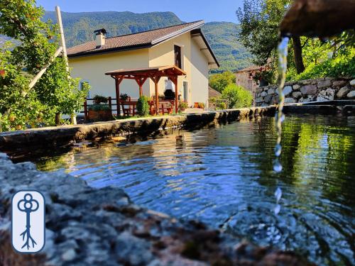 ein Haus mit einem Pavillon neben einem Wasserkörper in der Unterkunft Casa Vacanze Antico Eremo, tra natura e tradizione in Campodenno