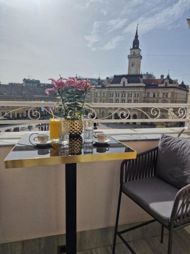 einen Tisch mit einer Blumenvase auf dem Balkon in der Unterkunft Queen Palace in Novi Sad