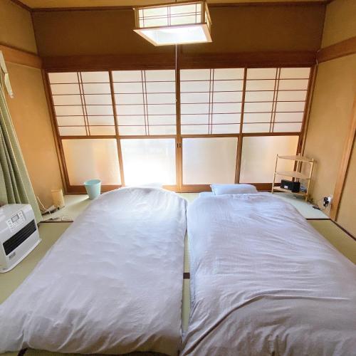 Cette chambre comprend un grand lit blanc et une fenêtre. dans l'établissement mooi 宮町, à Aizuwakamatsu