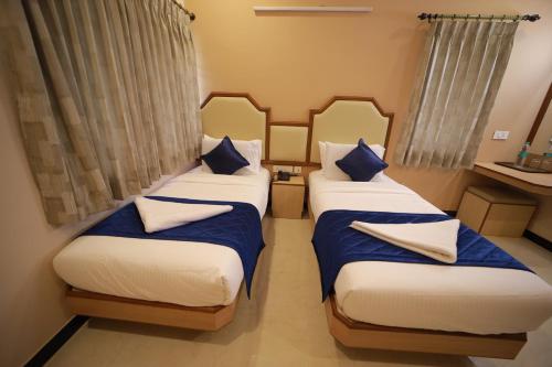 2 camas en una habitación pequeña con almohadas azules en Majestic Hotel, en Madurai