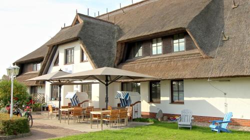 una casa con sillas, mesas y sombrilla en Mare Balticum Urlaub auf Rügen, en Sagard