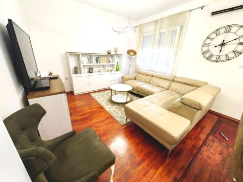 uma sala de estar com um sofá e um relógio na parede em Luxury apartment Podgorica em Podgorica