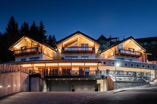 ein großes Haus mit beleuchteter Fassade in der Nacht in der Unterkunft La Dila Dolomiti Mountain Lodge in Andalo