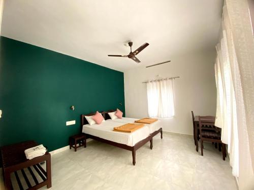 a bedroom with a bed and a green wall at Ammus Homestay in Thekkady