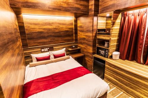 - une chambre avec un lit dans une pièce dotée de murs en bois dans l'établissement Petit Bali Forest Shinjuku Sanchōme, à Tokyo