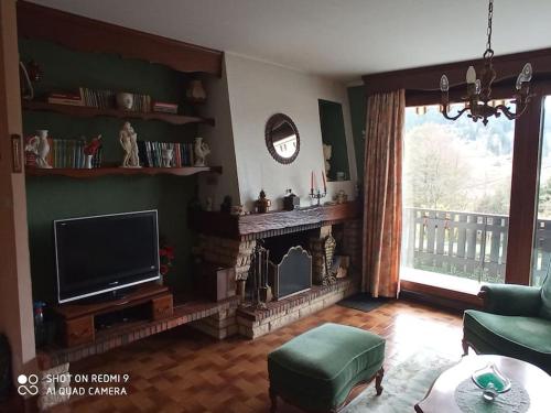 a living room with a television and a fireplace at Chez Vivi et Jean Pierre Maison 8 à 9 personnes au calme vue montagne WIFI in Gérardmer