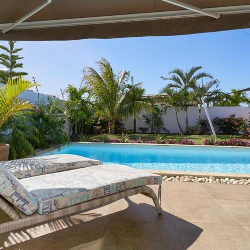 een bed op een patio naast een zwembad bij Villa Primera 3 bedroom bungalow with private pool Grand Bay in Grand Baie