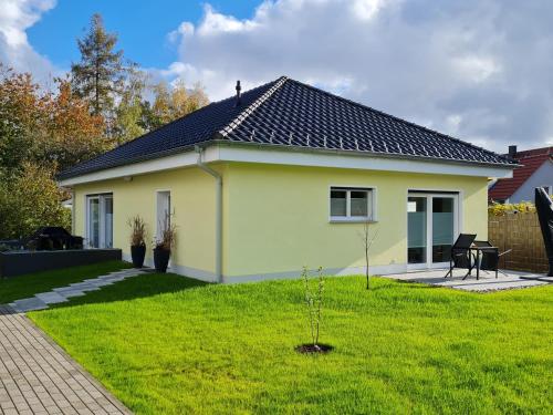 uma pequena casa amarela com um jardim verde em Ferienwohnung Jekarie em Veimar